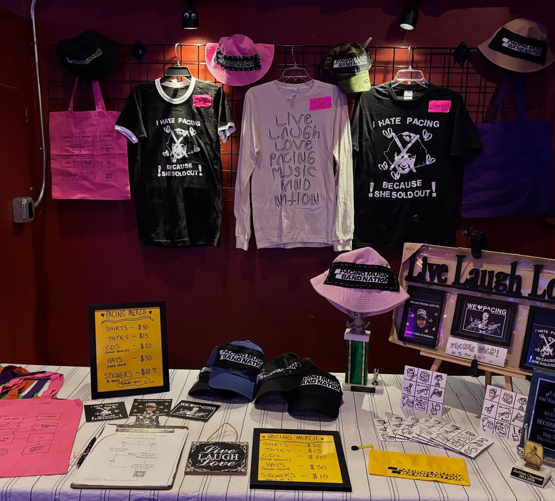 Merchandise booth at a Pacing show with an array of stickers, shirts, CDs, trophies, and bags.